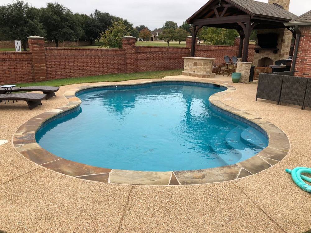 Freeform pool with pavilion and brick wall