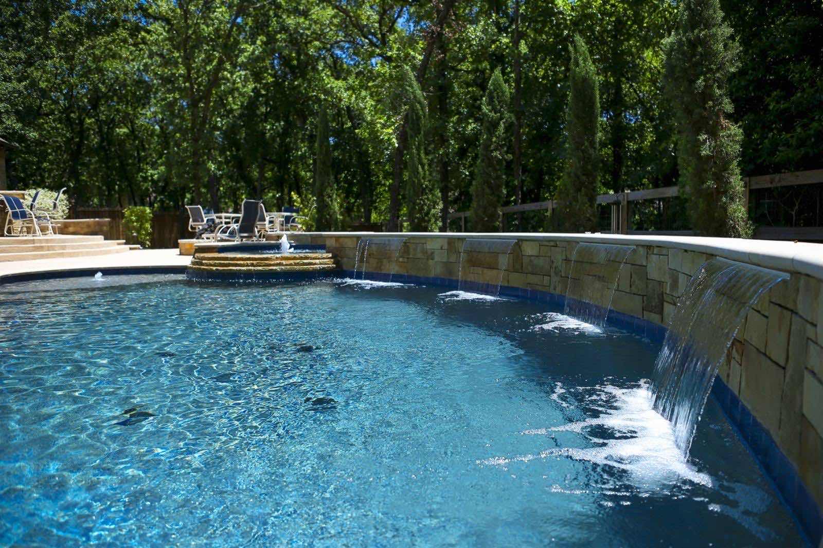 Remodeled pool with raised stone wall and sheer descent waterfalls